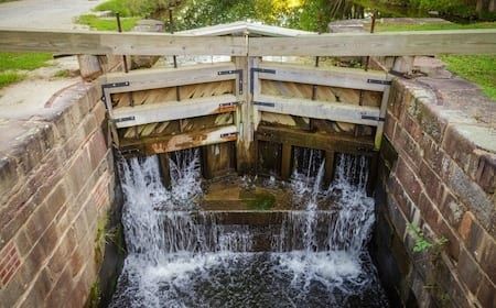 Petite écluse en pierre avec portes en bois et eau en cascade
