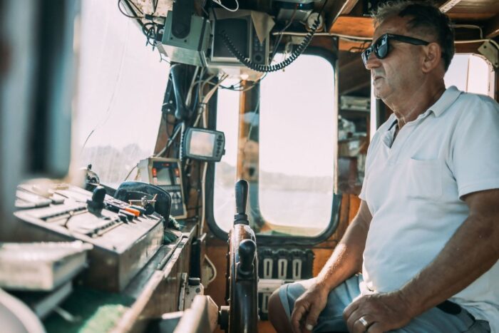 Homme aux commandes d’un bateau, devant les instruments de navigation